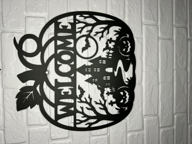 Black laser-cut Halloween welcome sign with haunted house and pumpkins