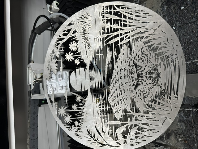 Intricate laser-cut metal artwork featuring an alligator and wetland scene
